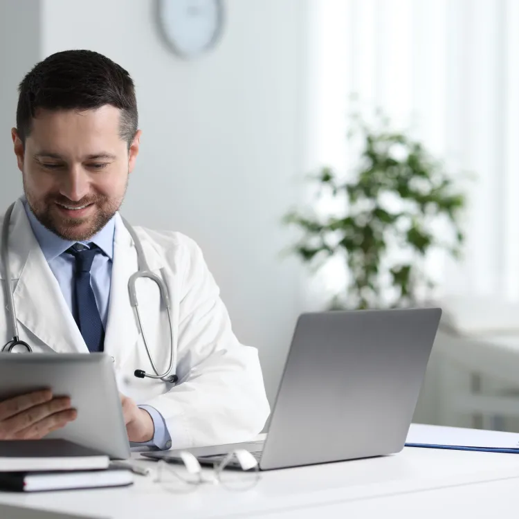 Doctor using a tablet and laptop for online compliance training